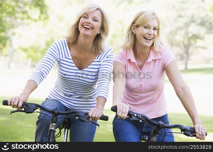 Two friends on bikes outdoors smiling