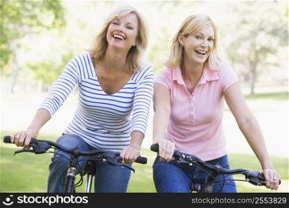 Two friends on bikes outdoors smiling