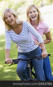 Two friends on one bike outdoors smiling