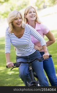 Two friends on one bike outdoors smiling