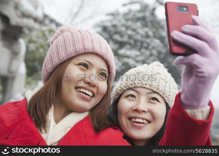 Two friends taking picture with cell phone in snow