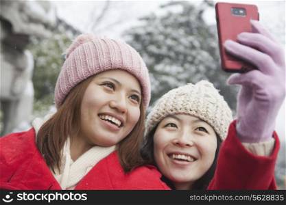 Two friends taking picture with cell phone in snow