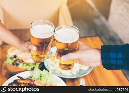 Two friends toasting and clinking with glass of beer.