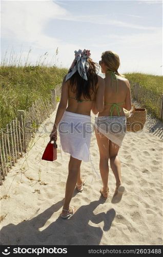 Two friends walking up path on beach