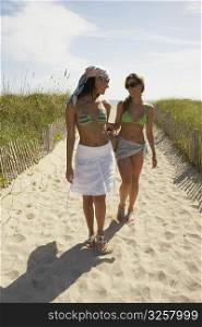 Two friends walking up path on beach