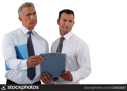 Two frowning businessmen holding clip-board