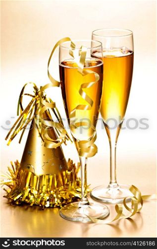 Two full champagne flutes with party hat and ribbons