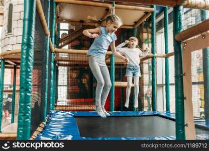 Two funny girls jumping on the trampoline, children game center. Excited childs having fun on playground indoors. Kids playing in amusement centre. Girls jumping on trampoline, children game center