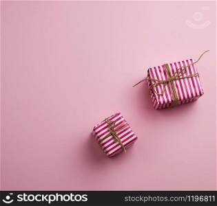 two gifts wrapped in pink striped paper on a pink background, top view, copy space
