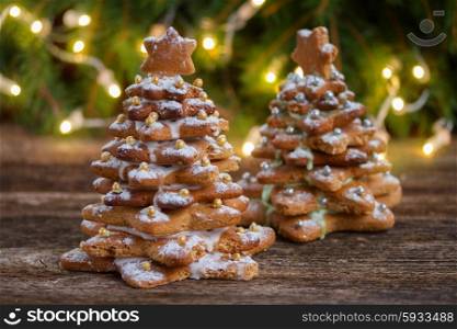 two gingerbread trees with christmas lights in background. gingerbread christmas tree