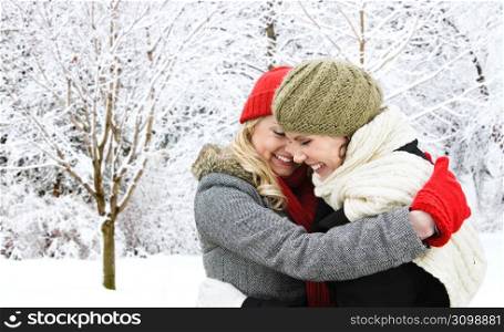 Two girl friends hugging outside in winter
