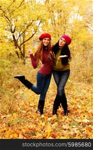 Two girl friends posing in the autumn forest