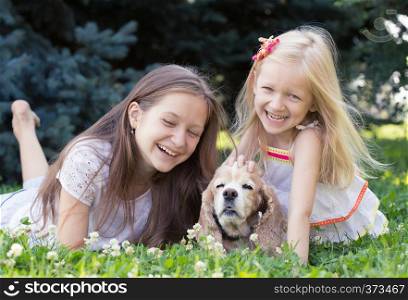 two girl sisters with dog lying on a grass