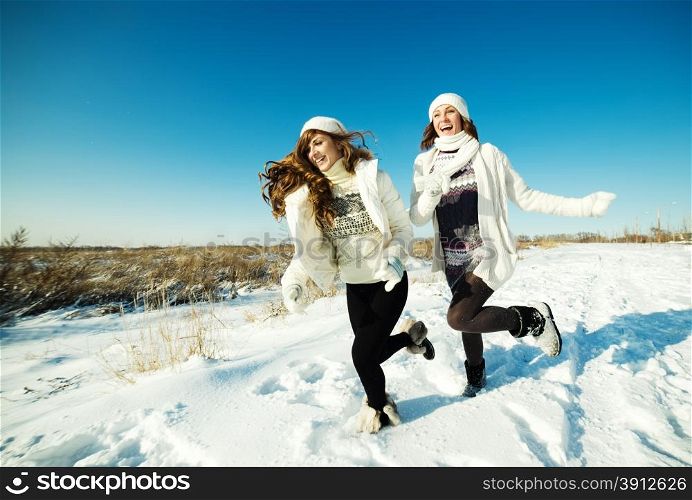 Two girlfriends have fun and enjoy fresh snow at beautiful winter day