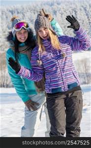Two girlfriends in winter snow mountains smiling and waving on camera