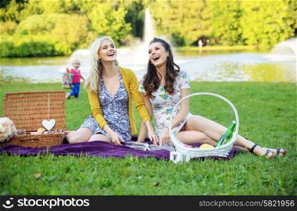 Two girlfriends laughing during summer picnic