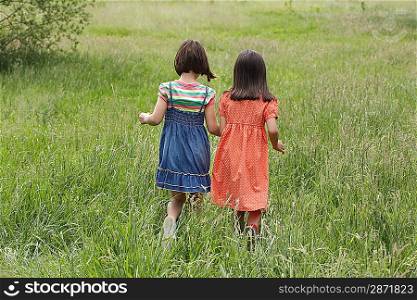 Two girls (7-9) holding hands in field