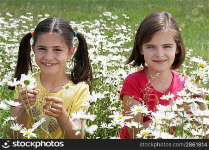 Two girls(7-9) standing among flowers in meadow, portrait
