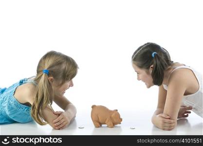 two girls and piggy bank isolated on white