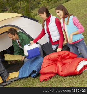 Two girls and their father near a tent