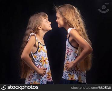 Two girls are standing opposite each other and putting their hands on their sides are looking at each other.