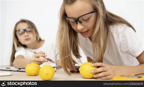 two girls doing science experiments with electricity lemons