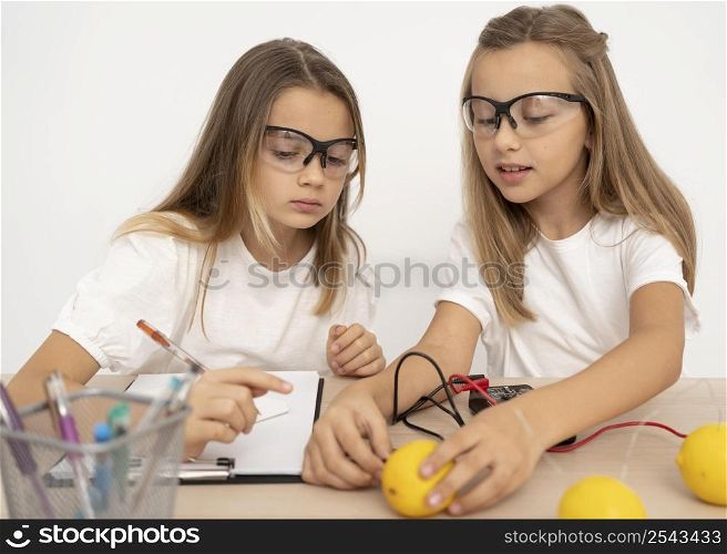 two girls doing science experiments with lemons