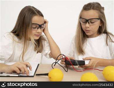 two girls doing science experiments with lemons electricity