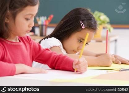 Two girls drawing in a classroom
