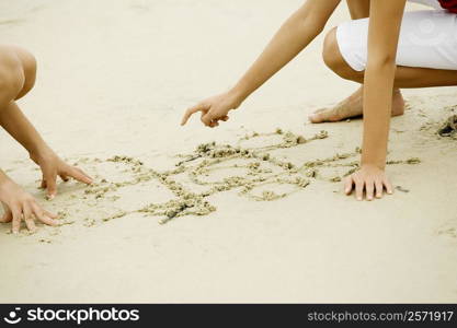 Two girls drawing in sand