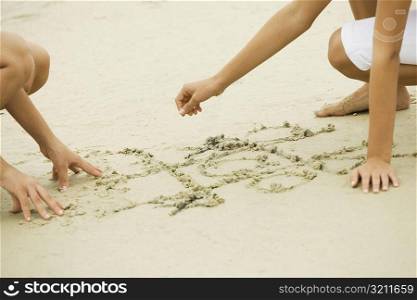 Two girls drawing in sand