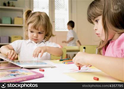 Two girls drawing on sheets of paper