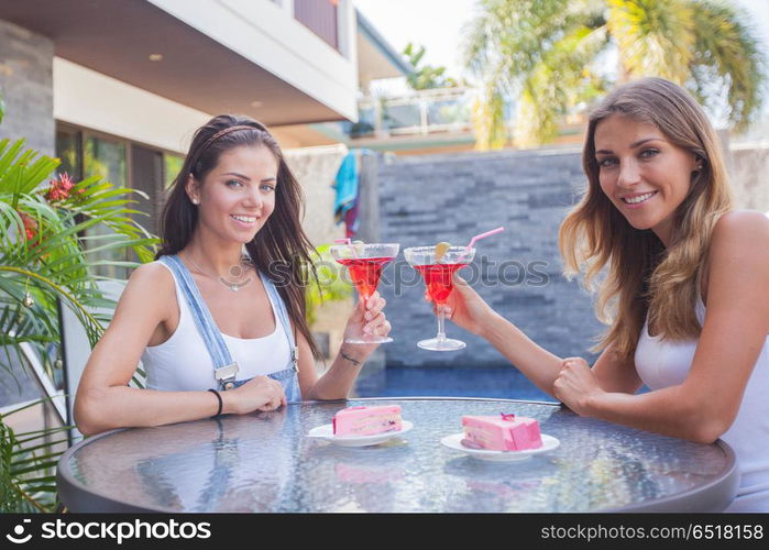 Two girls drink cocktails. Two girls, friends, the blonde and the brunette drink cocktails at the cafe at tropical resort cafe