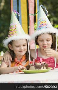 Two girls eating a birthday cake and smiling