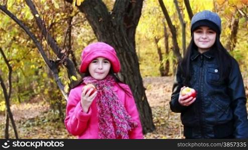 Two girls eating apples. Older sister gives her sister an apple.