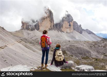 two girls hikers resting and looking at the rocks. tre cime di lavaredo
