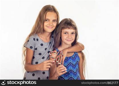 Two girls hugging made a heart out of two lollipops