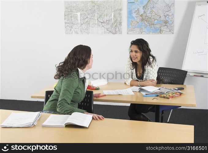 Two girls in a classroom chatting and not paying attention