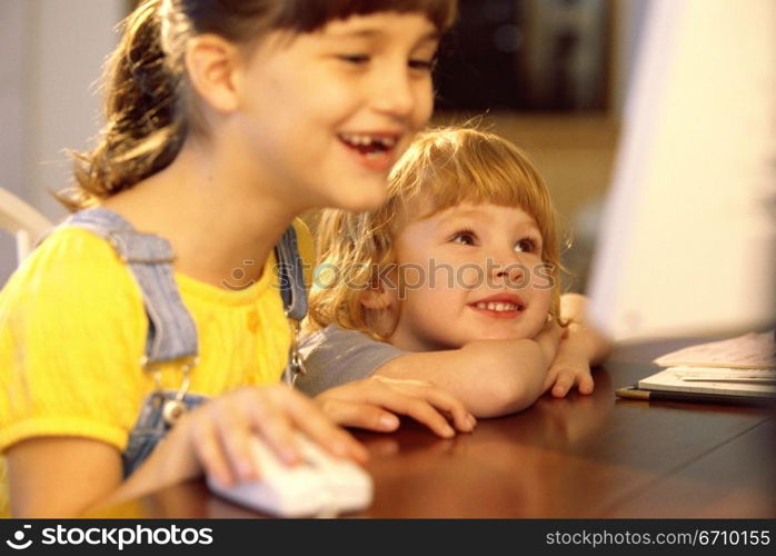 Two girls in front of a computer monitor