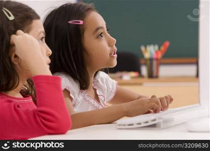 Two girls in front of a desktop PC in a classroom