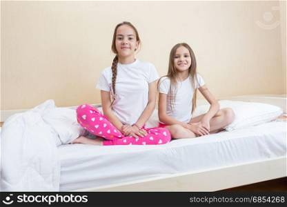 Two girls in pajamas sitting on bed