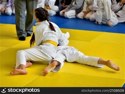 Two Girls judoka in kimono compete on the tatami