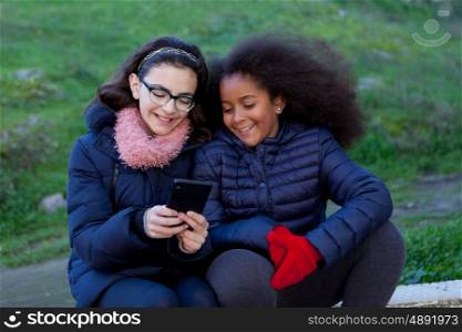 Two girls looking at the mobile in the park.