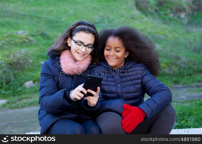 Two girls looking at the mobile in the park.