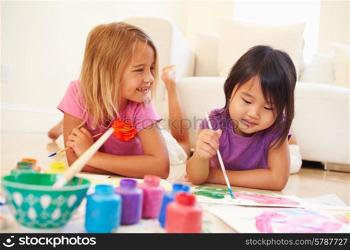 Two Girls Lying On Floor And Painting Picture At Home