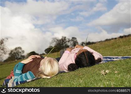Two girls lying on hillside