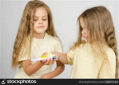 Two girls of four and six years of brushing their teeth toothbrushes. Girl squeezing toothpaste from a tube sister