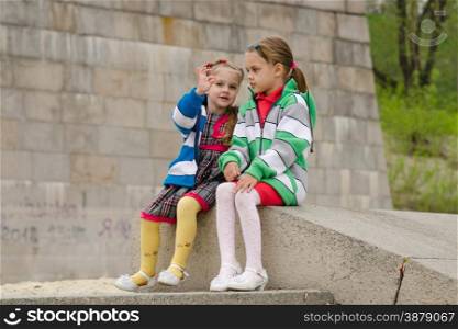 two girls of four and six years of walking on the embankment of the river