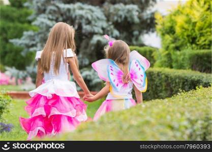Two girls of four and six years of walking through the green garden