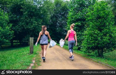 Two girls on back with garbage bags doing plogging. Two girls on back doing plogging